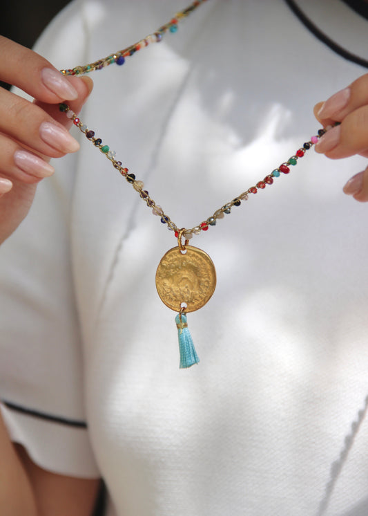 Collana lunga artigianale Laura Sciunnach con cristalli sfaccettati, ciondolo medaglia e nappina in tessuto – gioiello fatto a mano made in Italy.