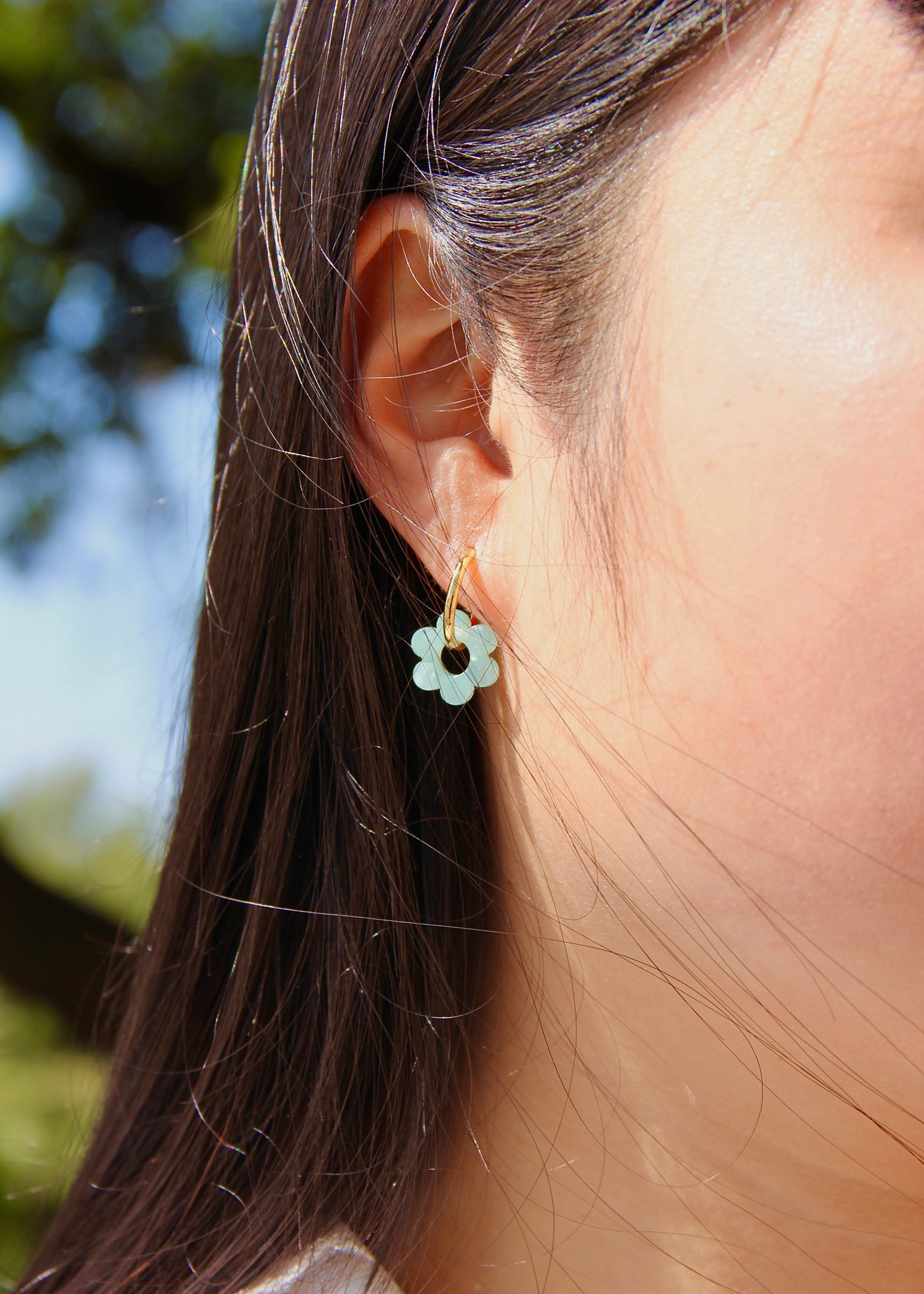 Orecchini ad anello in acciaio dorato con chiusura a scattino e ciondolo a forma di fiore in resina – colori rosa, azzurro, crema, arancione, fantasia blu-arancione e fantasia blu-verde – stile giocoso, primaverile ed estivo – bijoux leggeri e colorati.