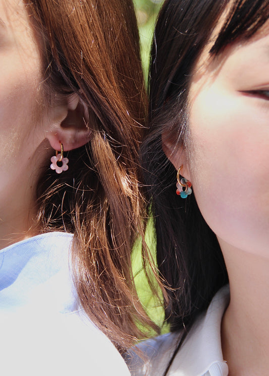 Orecchini ad anello in acciaio dorato con chiusura a scattino e ciondolo a forma di fiore in resina – colori rosa, azzurro, crema, arancione, fantasia blu-arancione e fantasia blu-verde – stile giocoso, primaverile ed estivo – bijoux leggeri e colorati.