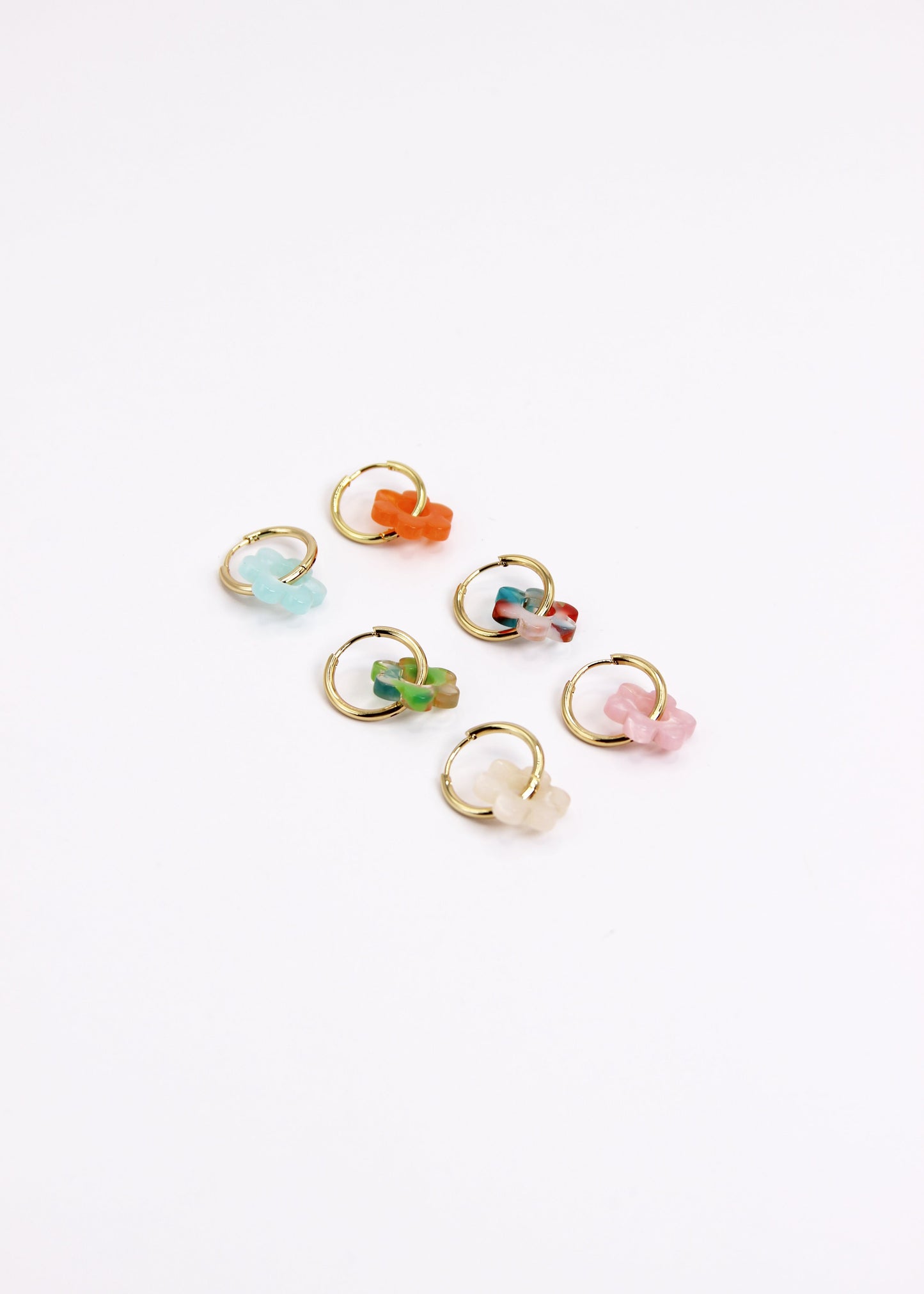 Orecchini ad anello in acciaio dorato con chiusura a scattino e ciondolo a forma di fiore in resina – colori rosa, azzurro, crema, arancione, fantasia blu-arancione e fantasia blu-verde – stile giocoso, primaverile ed estivo – bijoux leggeri e colorati.