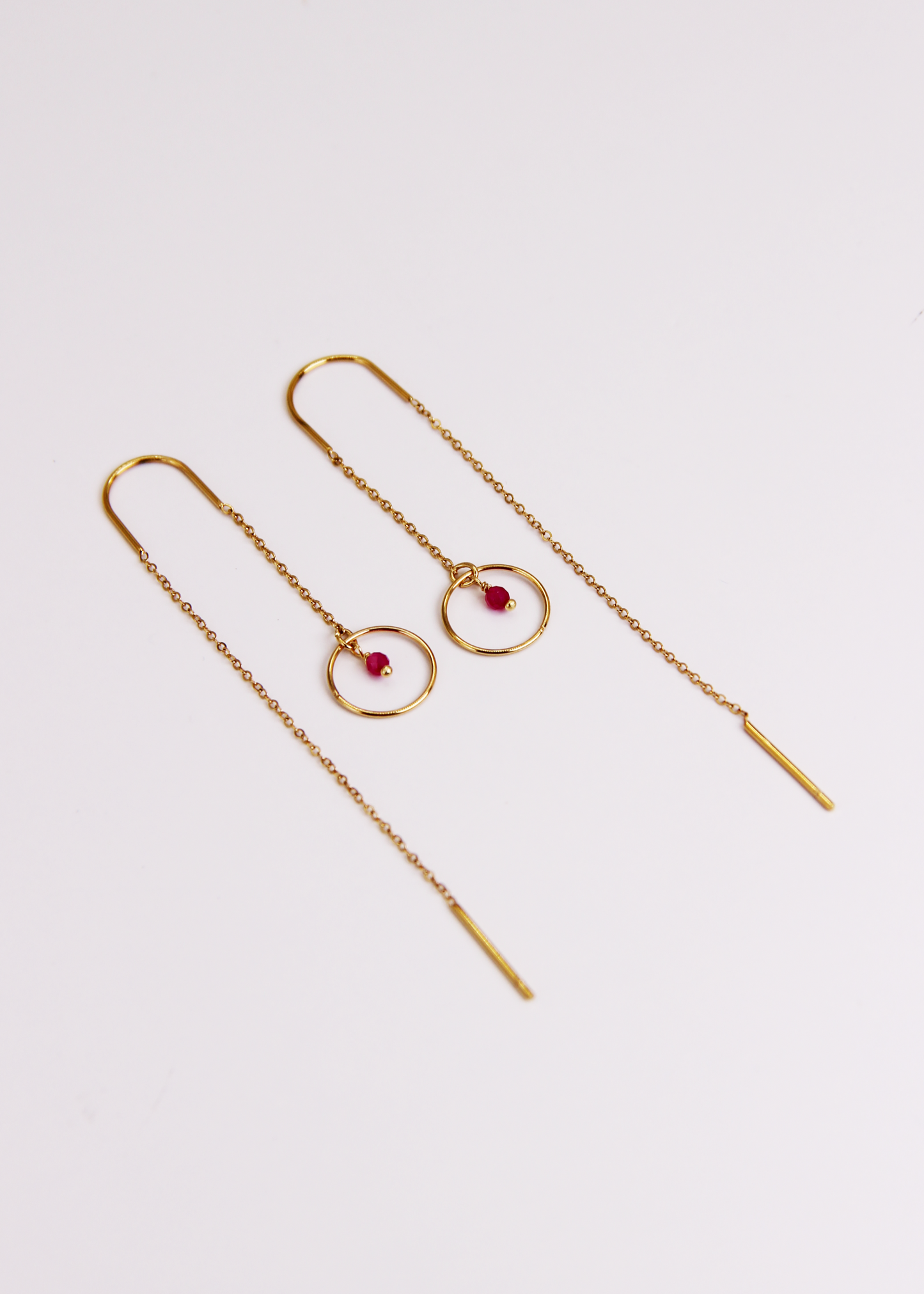 Orecchino saliscendi arco Saturno in acciaio dorato con archetto rigido, catena sottile e ciondolo a cerchio con pietra centrale, design elegante e minimalista.
