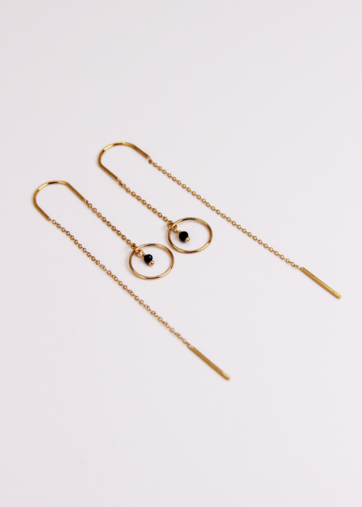 Orecchino saliscendi arco Saturno in acciaio dorato con archetto rigido, catena sottile e ciondolo a cerchio con pietra centrale, design elegante e minimalista.