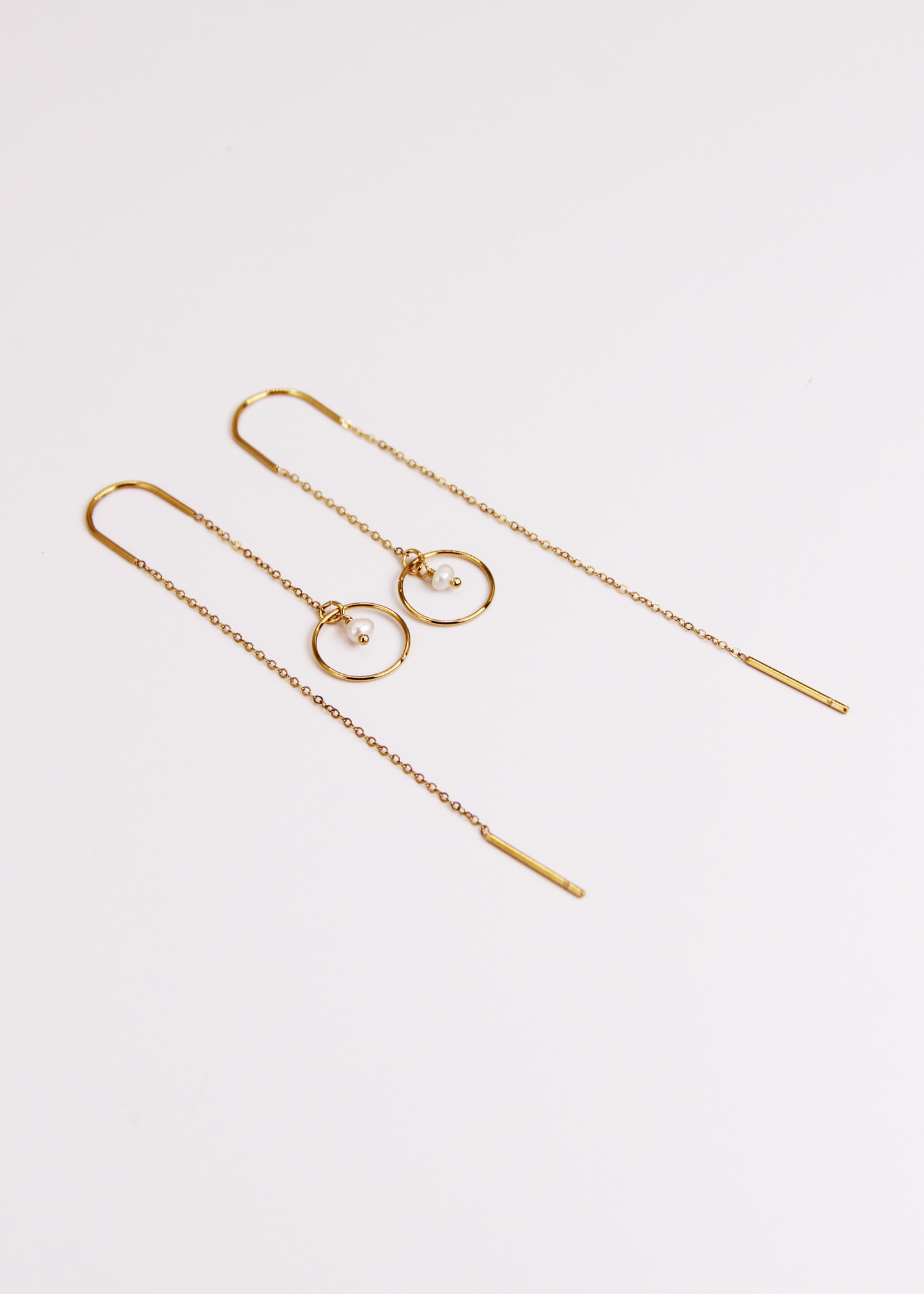 Orecchino saliscendi arco Saturno in acciaio dorato con archetto rigido, catena sottile e ciondolo a cerchio con pietra centrale, design elegante e minimalista.