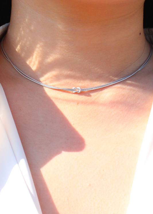 Collana in argento 925 con nodo, composta da due fili intrecciati. Disponibile anche in versione placcata oro. La lunghezza della collana è regolabile, per una vestibilità personalizzata