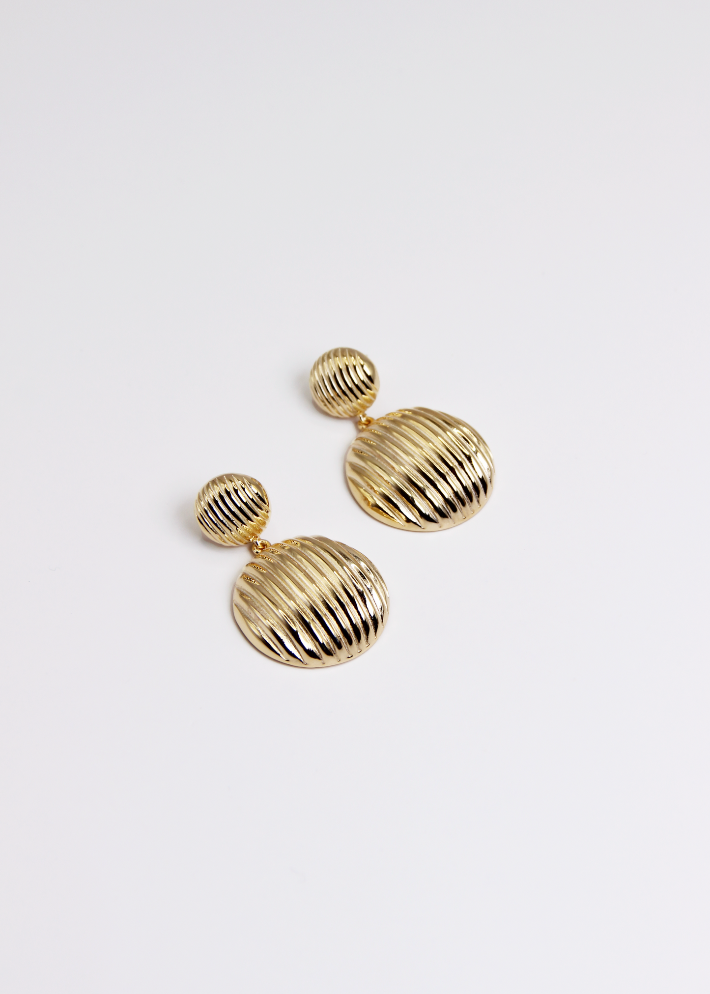 Orecchino pendente chunky con chiusura a perno, composto da due bottoni con texture rigata. Realizzato in argento 925, disponibile anche placcato oro per un tocco di eleganza in più. La lunghezza totale dell'orecchino è di 3,8 cm, con un diametro del bottone inferiore di 2,3 cm, ideale per un look sofisticato e moderno.