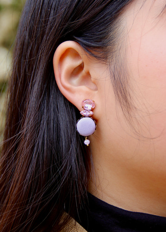 Orecchino artigianale Metropolitan realizzato da laura sciunnach bijoux modello Venezia con bottone in stoffa lilla, cristalli tagliati e perlina pendente – gioiello fatto a mano, leggero e personalizzabile, ispirato alla città di Venezia.