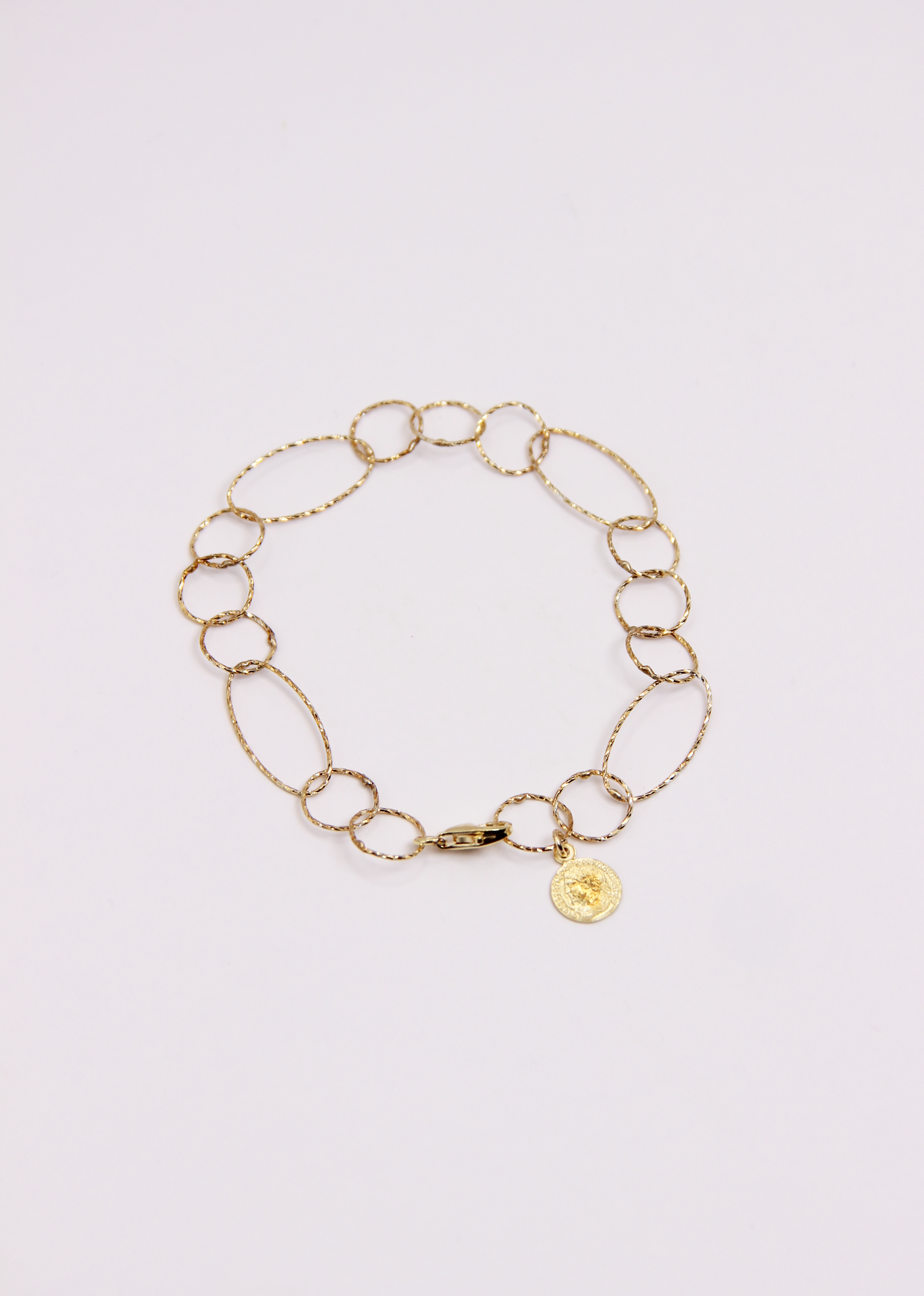 Bracciale Intreccio mono filo di Laura Sciunnach, artigianale, un unico filo a maglie irregolari in argento 925, oro giallo o oro rosa, con piccola monetina pendente, minimalista ed elegante, gioiello contemporaneo.