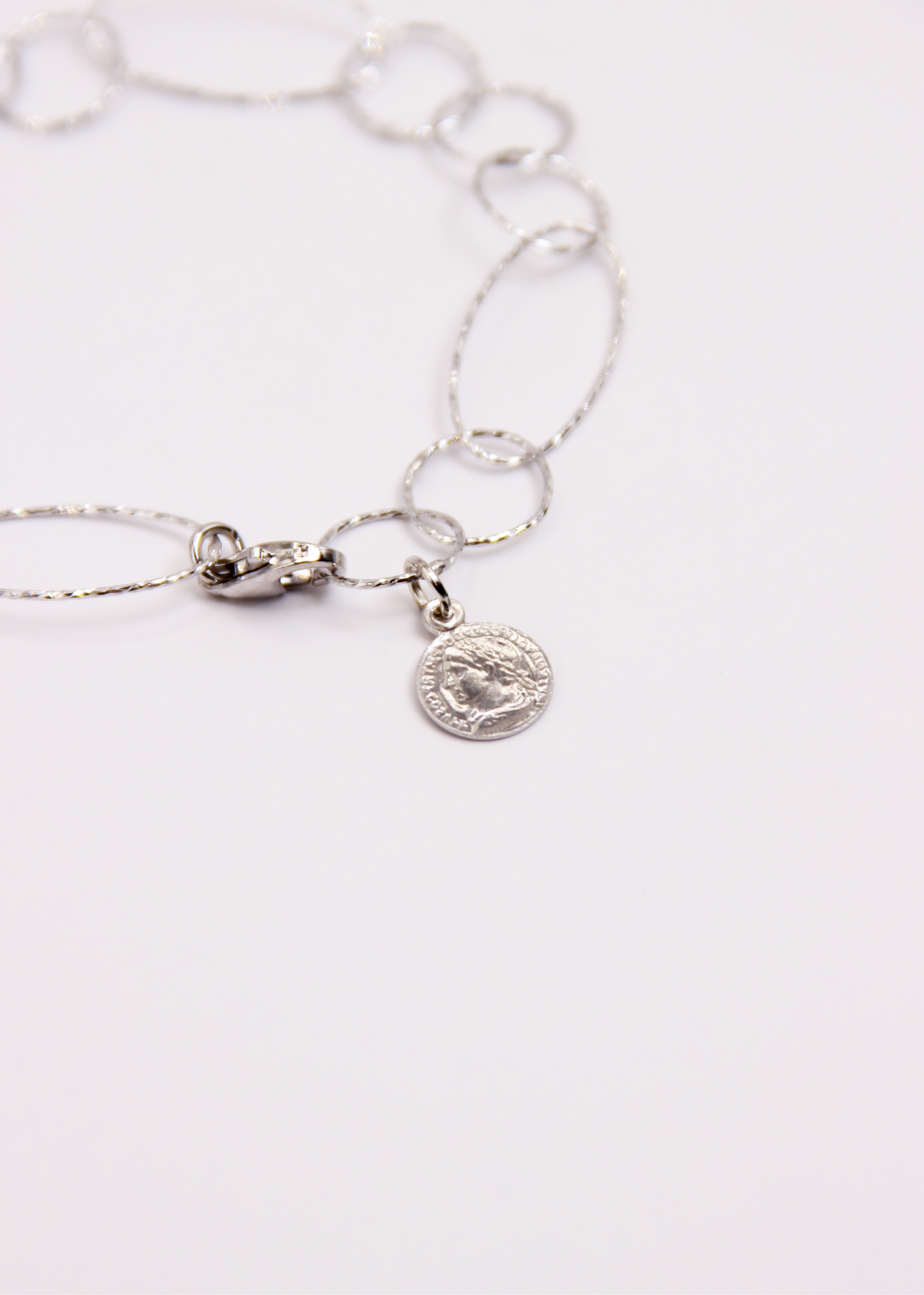 Bracciale Intreccio mono filo di Laura Sciunnach, artigianale, un unico filo a maglie irregolari in argento 925, oro giallo o oro rosa, con piccola monetina pendente, minimalista ed elegante, gioiello contemporaneo.