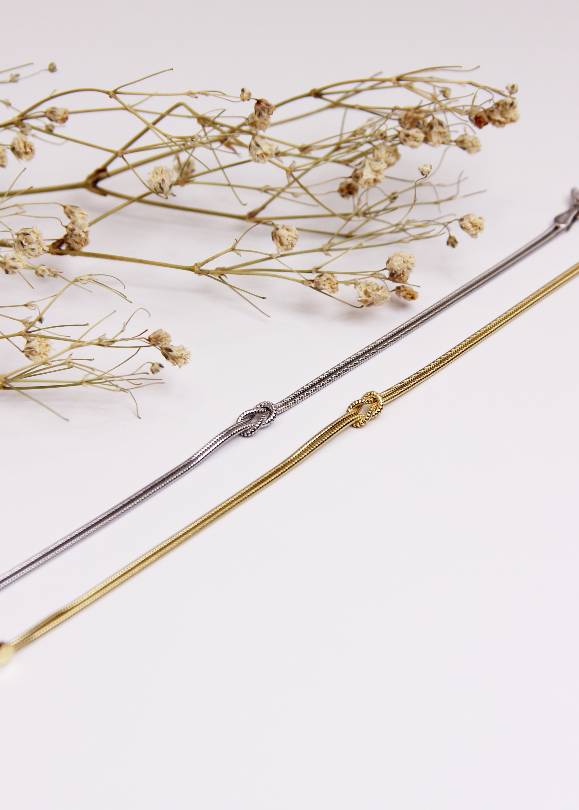 Bracciale in argento 925 con nodo, composto da due fili intrecciati. Disponibile anche in versione placcato oro. La lunghezza del bracciale è regolabile, per una vestibilità personalizzata.