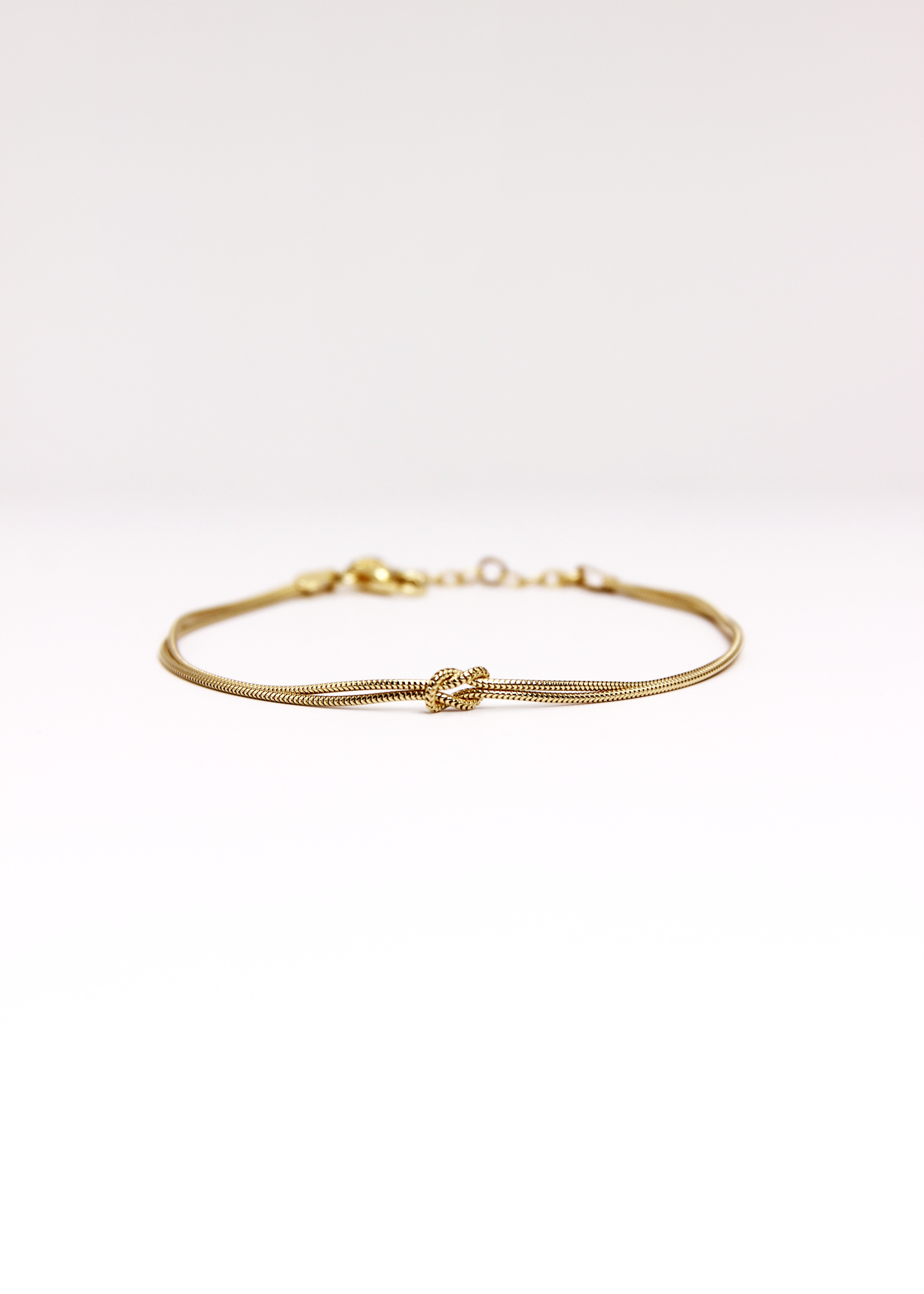 Bracciale in argento 925 con nodo, composto da due fili intrecciati. Disponibile anche in versione placcato oro. La lunghezza del bracciale è regolabile, per una vestibilità personalizzata.