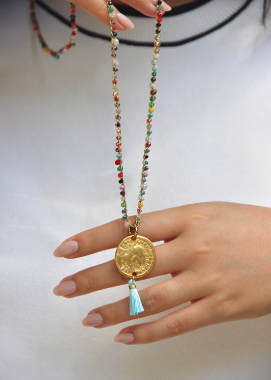 Collana lunga artigianale Laura Sciunnach con cristalli sfaccettati, ciondolo medaglia e nappina in tessuto – gioiello fatto a mano made in Italy.