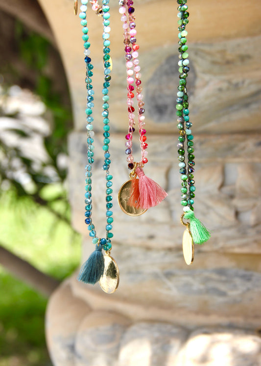 Collana lunga artigianale Laura Sciunnach con cristalli sfaccettati, ciondolo a forma di moneta e nappina in tessuto – gioiello fatto a mano made in Italy.