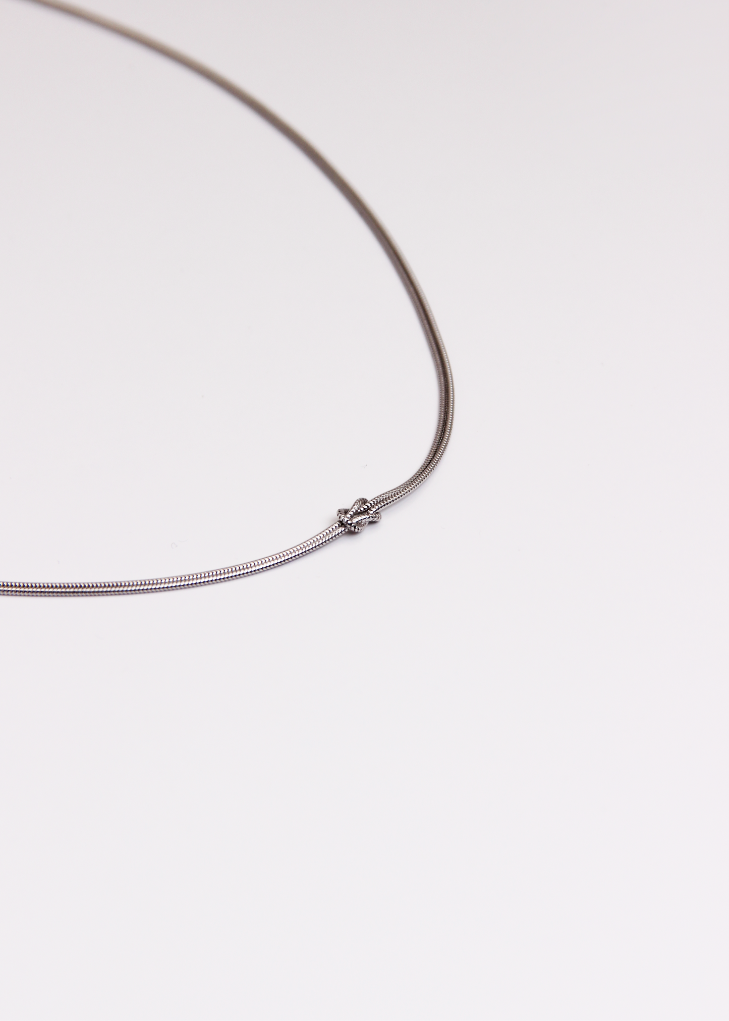 Collana in argento 925 con nodo, composta da due fili intrecciati. Disponibile anche in versione placcata oro. La lunghezza della collana è regolabile, per una vestibilità personalizzata