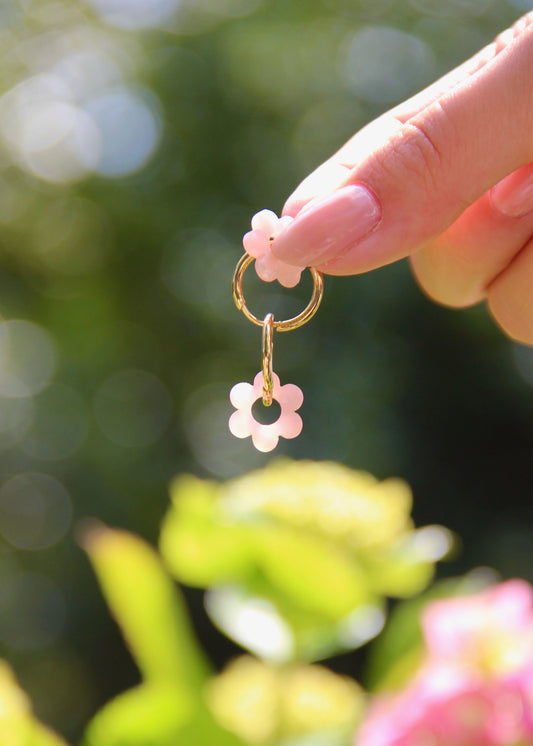 Orecchini ad anello in acciaio dorato con chiusura a scattino e ciondolo a forma di fiore in resina – colori rosa, azzurro, crema, arancione, fantasia blu-arancione e fantasia blu-verde – stile giocoso, primaverile ed estivo – bijoux leggeri e colorati.