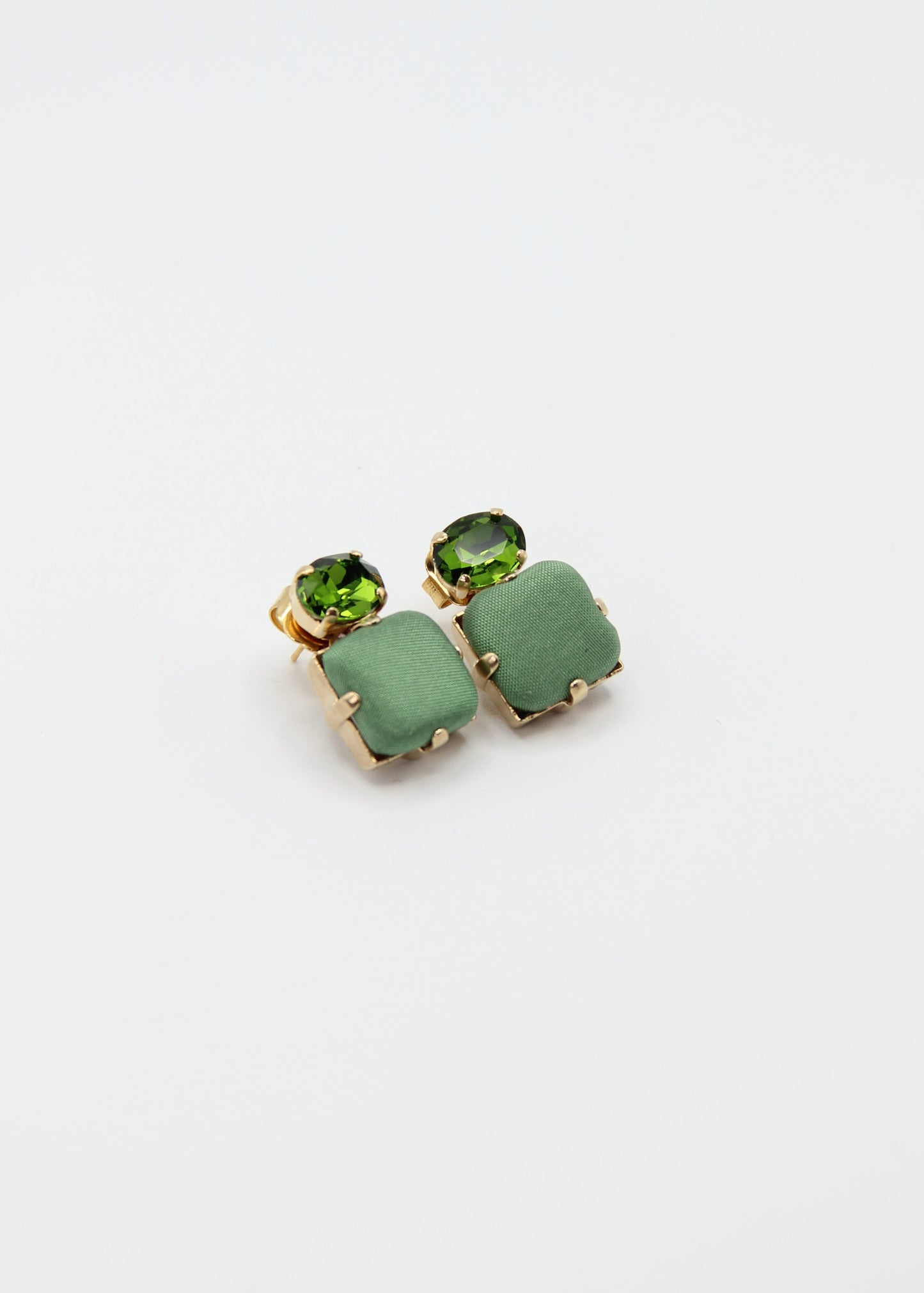 Orecchini verde salvia eleganti fatti a mano da Laura Sciunnach Bijoux, modello Metropolitan Siviglia con bottone quadrato in stoffa verde salvia e cristallo ovale verde tono su tono, design geometrico leggero e raffinato.