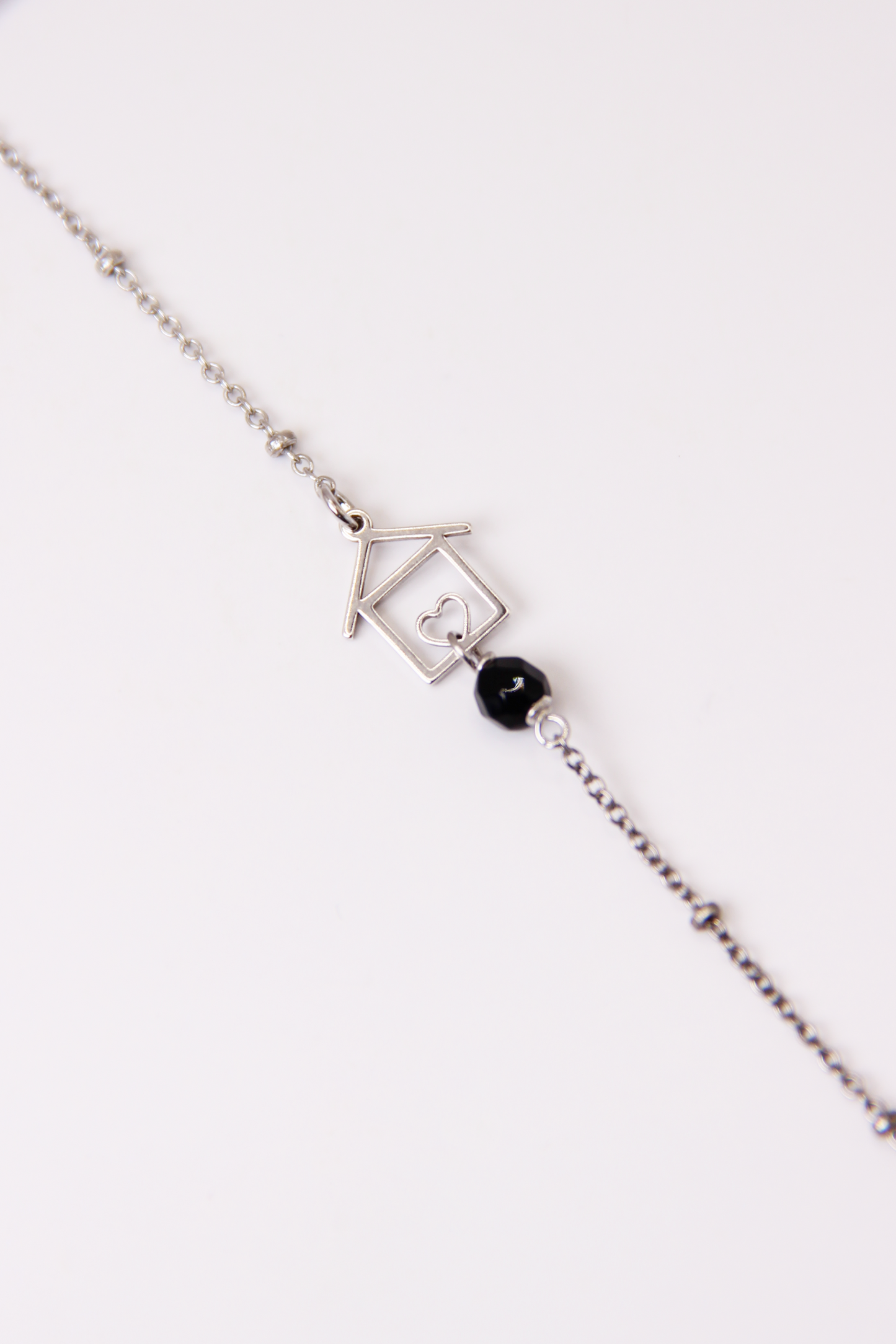 Bracciale artigianale fatto a mano da Laura Sciunnach Bijoux in argento 925, con catena rosario e ciondolo a forma di casetta con pietra dura naturale. Disponibile in perla di lago, radice di rubino, agata nera e agata verde, e nelle varianti argento, argento placcato oro e oro rosa. Chiusura a moschettone, lunghezza regolabile