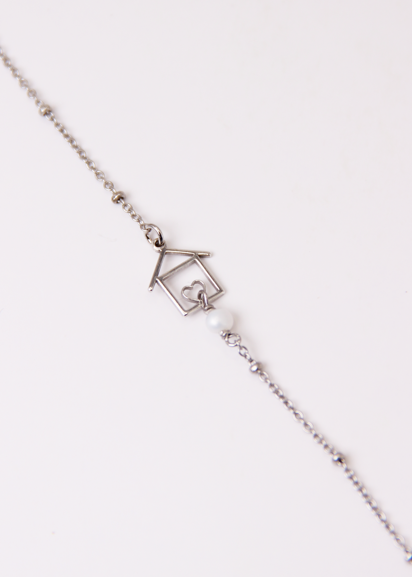 Bracciale artigianale fatto a mano da Laura Sciunnach Bijoux in argento 925, con catena rosario e ciondolo a forma di casetta con pietra dura naturale. Disponibile in perla di lago, radice di rubino, agata nera e agata verde, e nelle varianti argento, argento placcato oro e oro rosa. Chiusura a moschettone, lunghezza regolabile