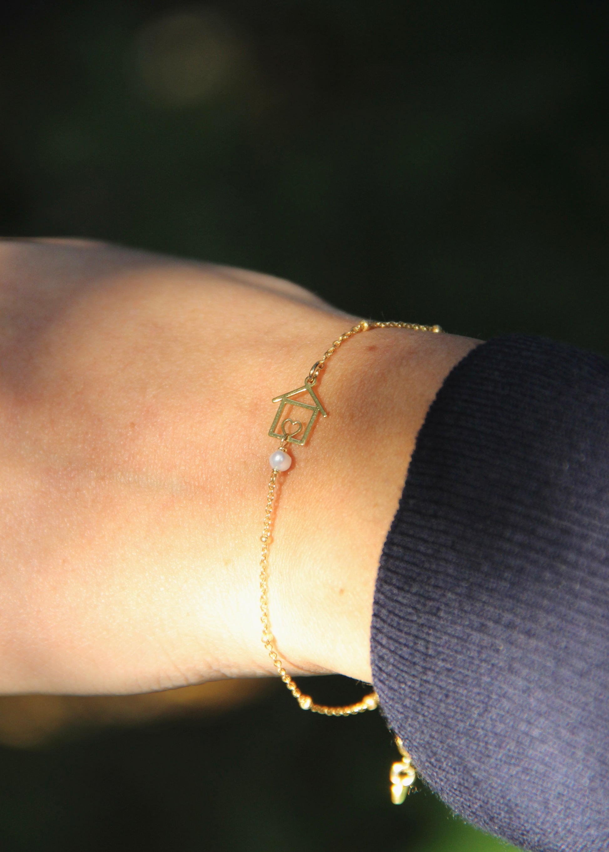 Bracciale artigianale fatto a mano da Laura Sciunnach Bijoux in argento 925, con catena rosario e ciondolo a forma di casetta con pietra dura naturale. Disponibile in perla di lago, radice di rubino, agata nera e agata verde, e nelle varianti argento, argento placcato oro e oro rosa. Chiusura a moschettone, lunghezza regolabile