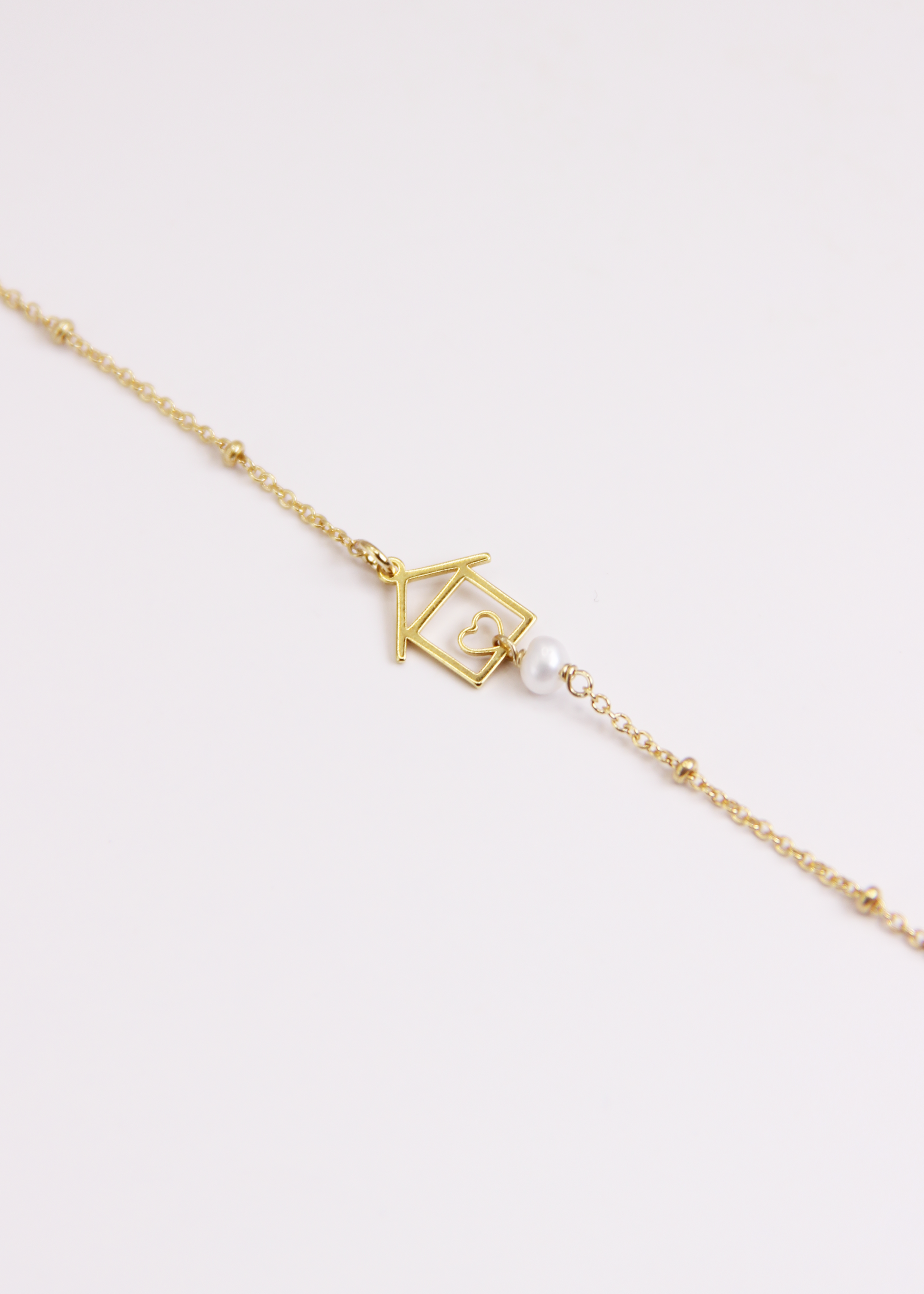 Bracciale artigianale fatto a mano da Laura Sciunnach Bijoux in argento 925, con catena rosario e ciondolo a forma di casetta con pietra dura naturale. Disponibile in perla di lago, radice di rubino, agata nera e agata verde, e nelle varianti argento, argento placcato oro e oro rosa. Chiusura a moschettone, lunghezza regolabile