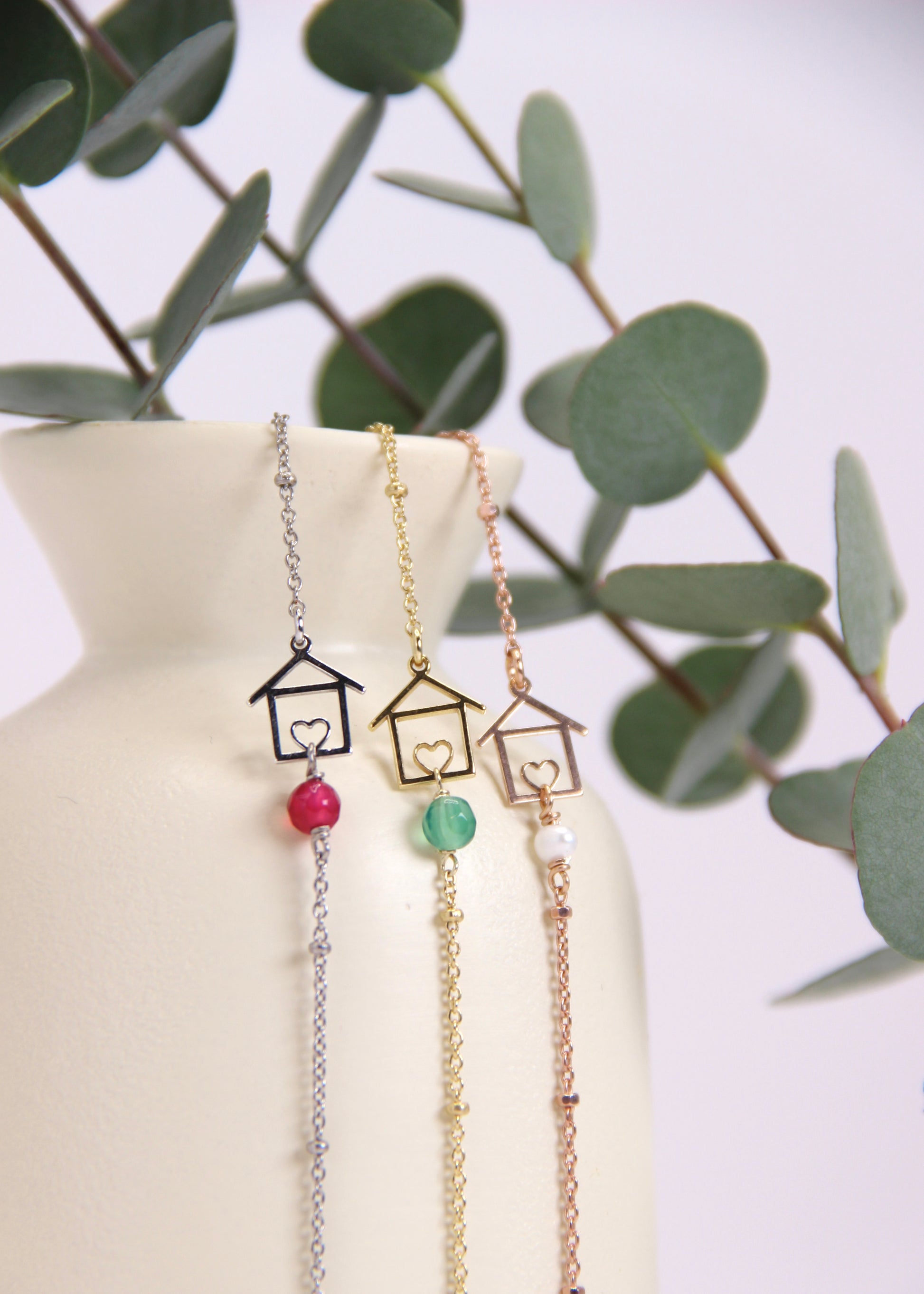 Bracciale artigianale fatto a mano da Laura Sciunnach Bijoux in argento 925, con catena rosario e ciondolo a forma di casetta con pietra dura naturale. Disponibile in perla di lago, radice di rubino, agata nera e agata verde, e nelle varianti argento, argento placcato oro e oro rosa. Chiusura a moschettone, lunghezza regolabile