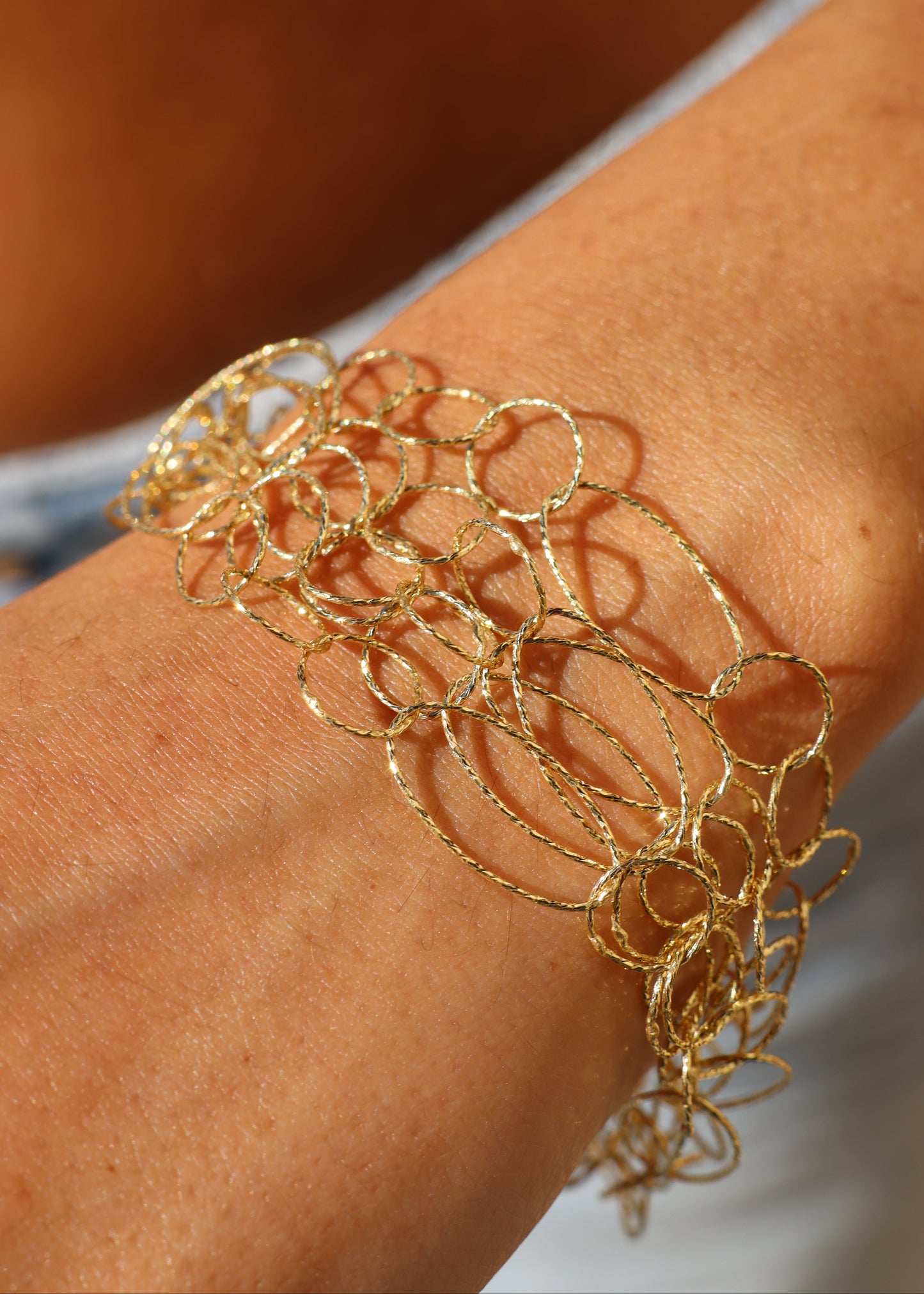 Bracciale Intreccio di Laura Sciunnach, artigianale, cinque fili a maglie irregolari in argento 925, oro giallo o oro rosa, con piccola monetina pendente, elegante e contemporaneo.