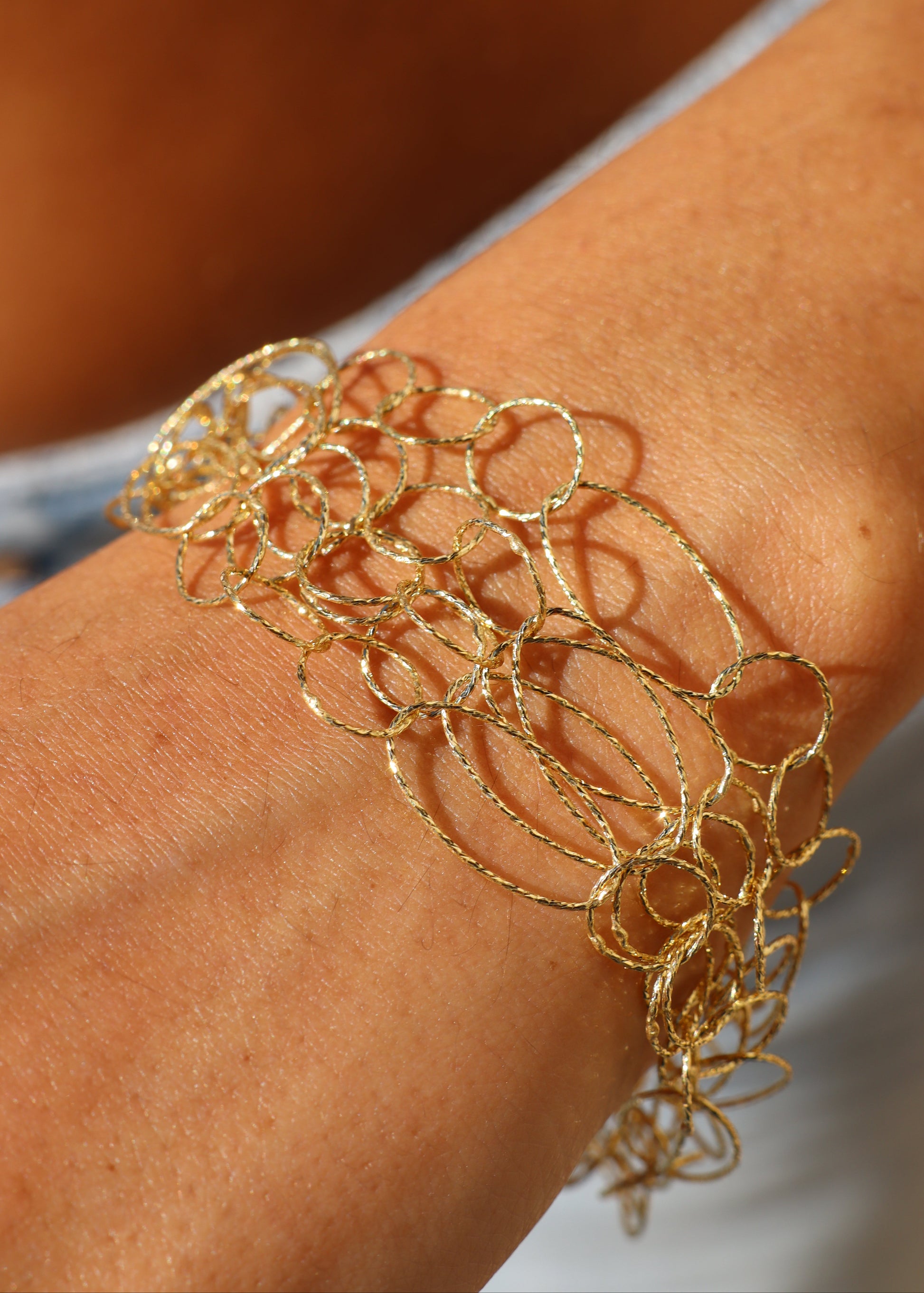 Bracciale Intreccio di Laura Sciunnach, artigianale, cinque fili a maglie irregolari in argento 925, oro giallo o oro rosa, con piccola monetina pendente, elegante e contemporaneo.