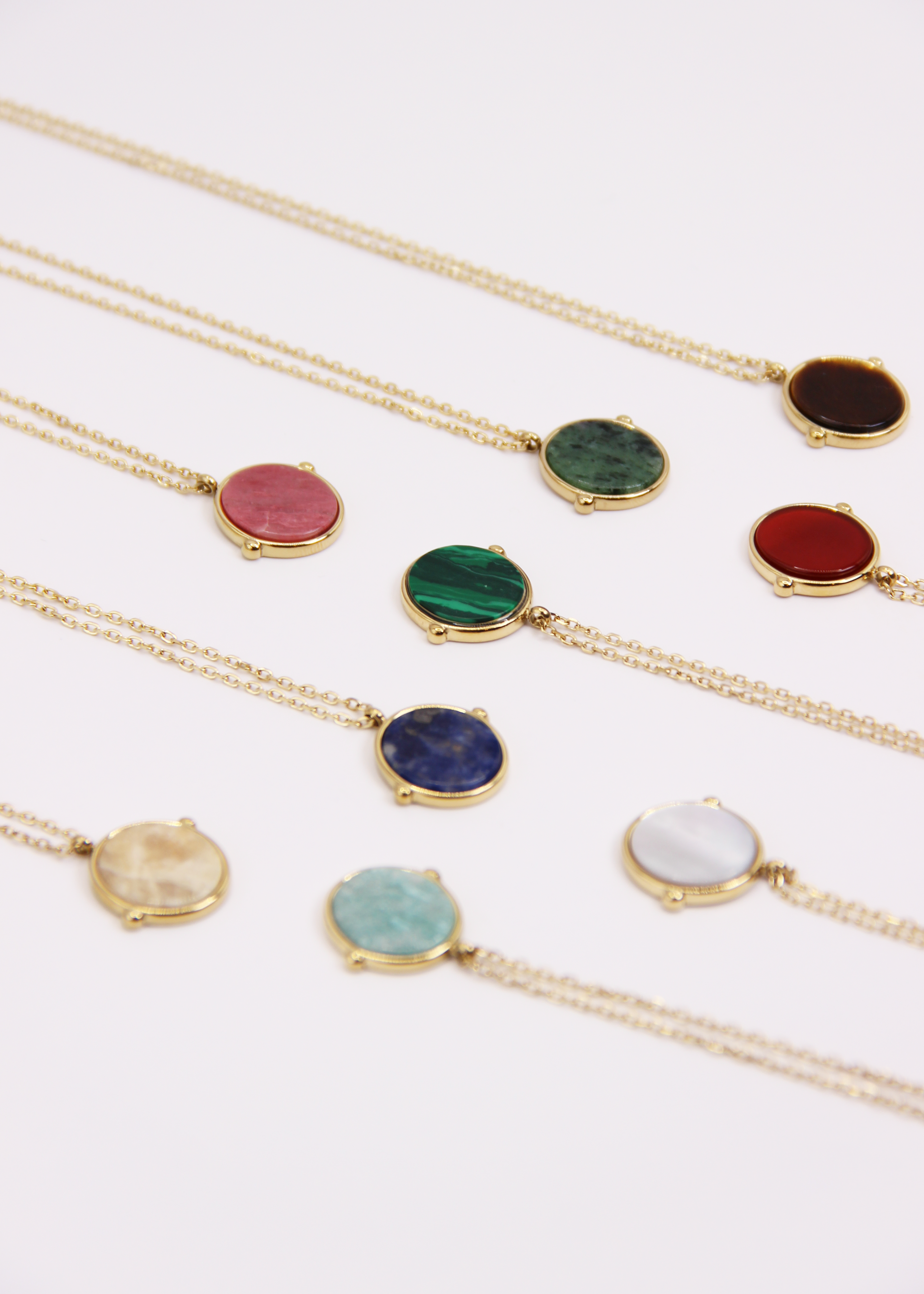 Collana in acciaio placcato oro con ciondolo ovale in pietra dura naturale e catena a maglia rettangolare fine. Disponibile in diversi colori, dal design elegante e senza tempo. Ogni pietra presenta variazioni naturali di colore e venature