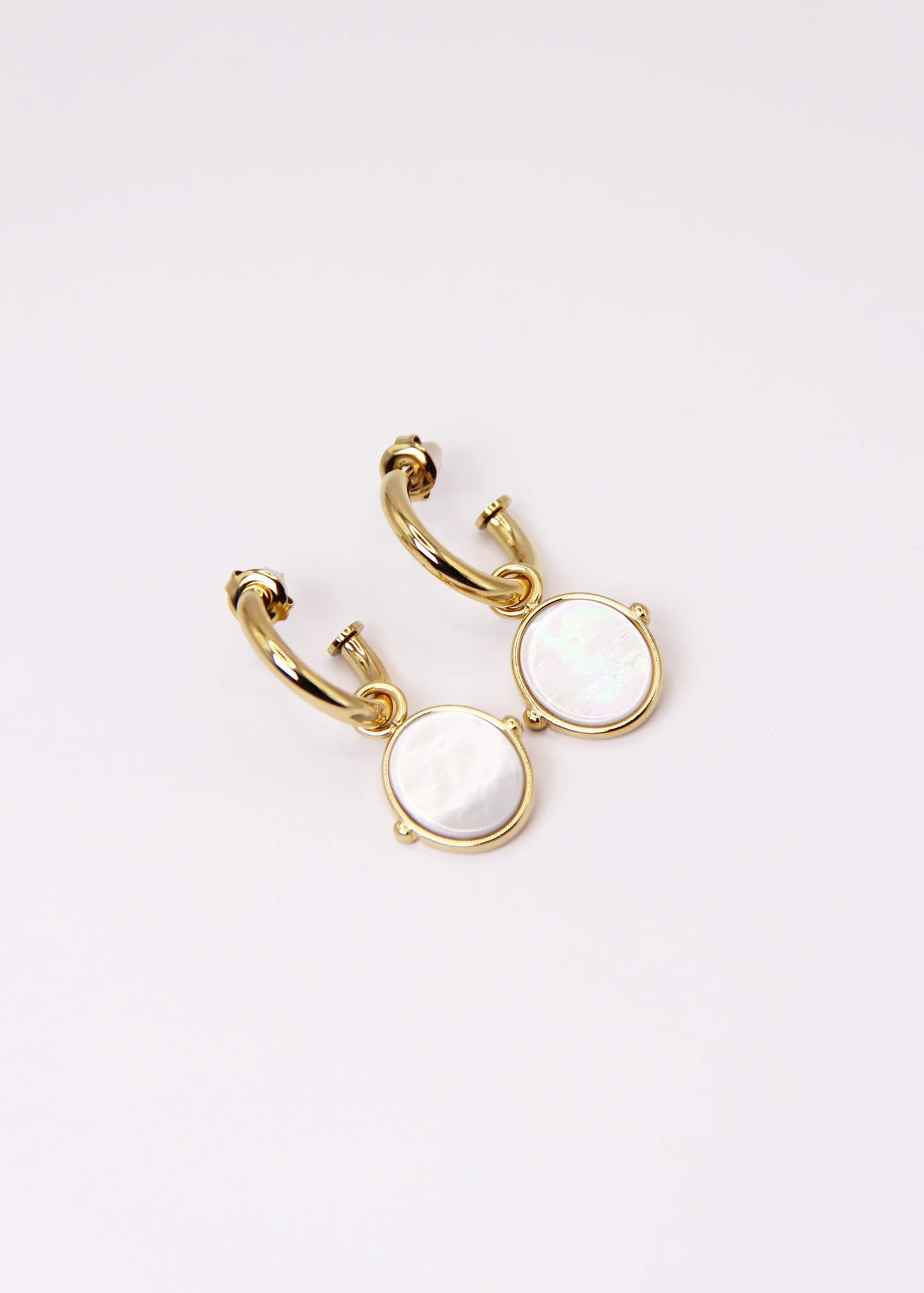 Orecchini a cerchio in acciaio placcato oro con pendente ovale in pietra dura naturale. Modello elegante con chiusura a perno, disponibile in vari colori tra cui occhio di tigre, malachite e opalite. Ogni pietra presenta leggere variazioni naturali di colore e venature.