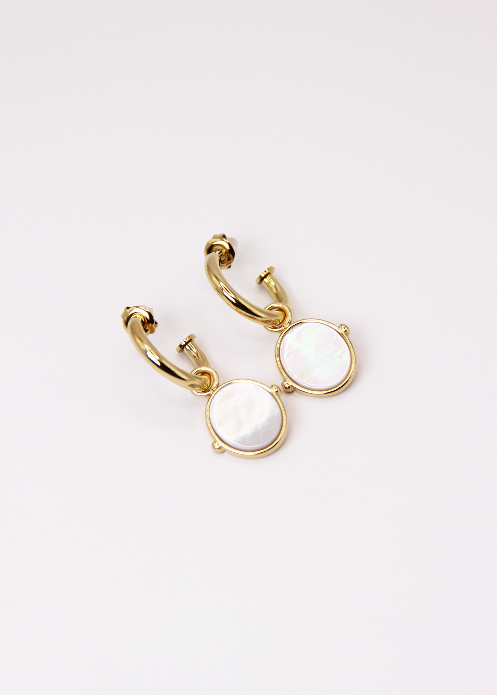 Orecchini a cerchio in acciaio placcato oro con pendente ovale in pietra dura naturale. Modello elegante con chiusura a perno, disponibile in vari colori tra cui occhio di tigre, malachite e opalite. Ogni pietra presenta leggere variazioni naturali di colore e venature.