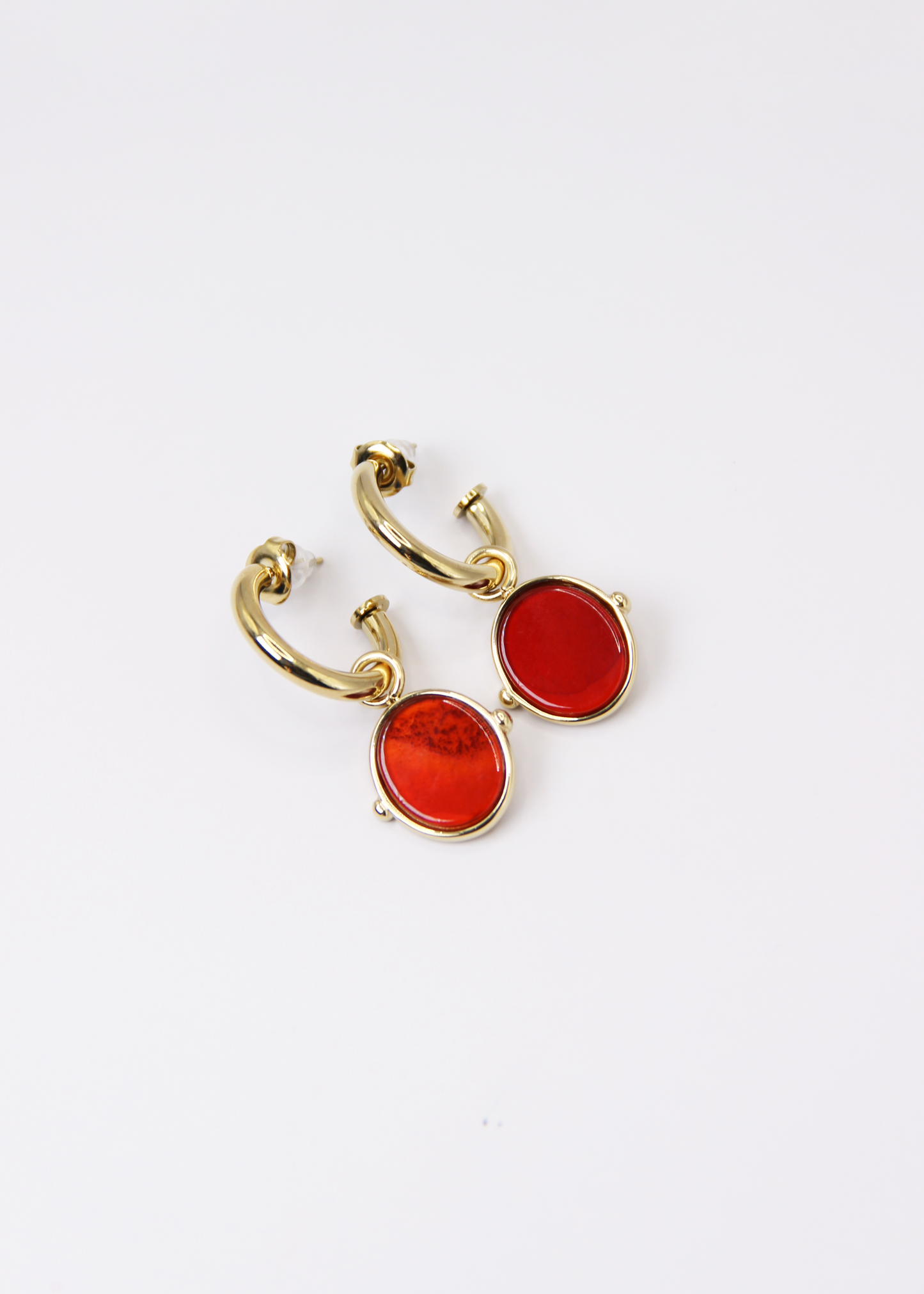 Orecchini a cerchio in acciaio placcato oro con pendente ovale in pietra dura naturale. Modello elegante con chiusura a perno, disponibile in vari colori tra cui occhio di tigre, malachite e opalite. Ogni pietra presenta leggere variazioni naturali di colore e venature.