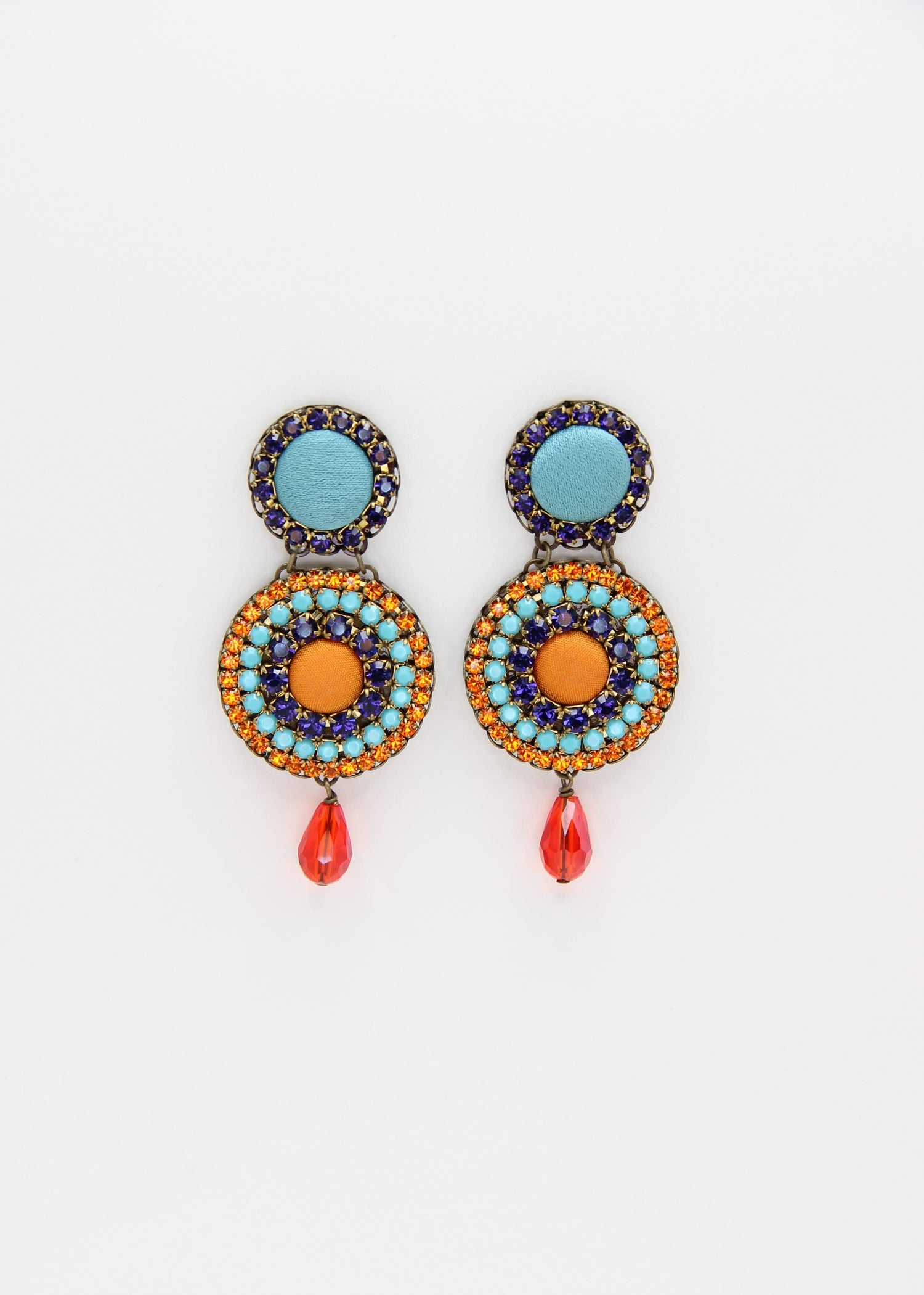 Orecchini artigianali Metropolitan Dubai blu e arancione, con bottoni circolari in tessuto azzurro, cristalli in gradiente blu, arancione e azzurro e pendente a goccia in cristallo. Nickel free, ideali per cerimonie ed eventi speciali.