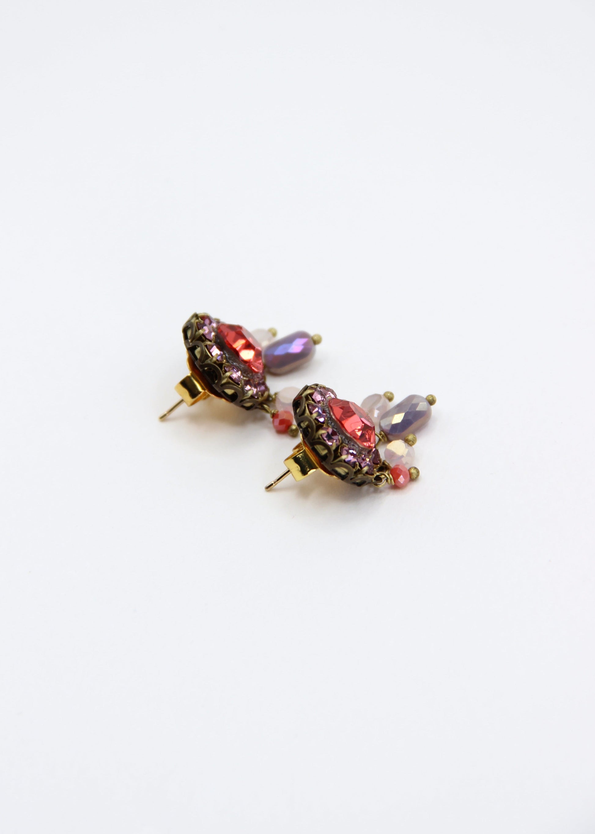 Orecchini artigianali Metropolitan Taormina rosso e malva, con cristallo centrale rosso, corona di strass malva e cinque pietre sfaccettate iridescenti a cascata. Nickel free, stile mediterraneo per ogni occasione.