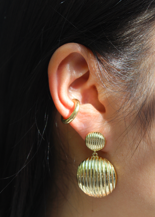 Orecchino pendente chunky con chiusura a perno, composto da due bottoni con texture rigata. Realizzato in argento 925, disponibile anche placcato oro per un tocco di eleganza in più. La lunghezza totale dell'orecchino è di 3,8 cm, con un diametro del bottone inferiore di 2,3 cm, ideale per un look sofisticato e moderno.