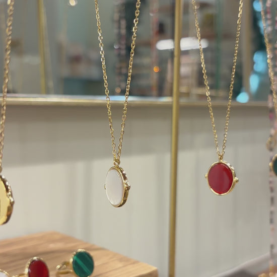 Collana in acciaio placcato oro con ciondolo ovale in pietra dura naturale e catena a maglia rettangolare fine. Disponibile in diversi colori, dal design elegante e senza tempo. Ogni pietra presenta variazioni naturali di colore e venature